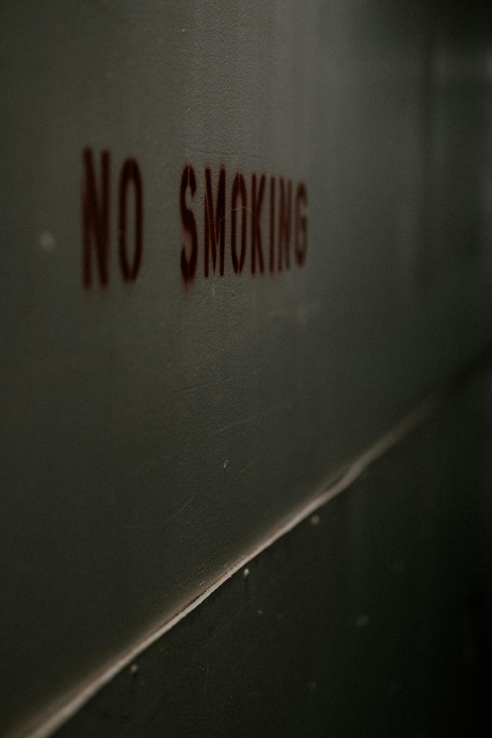 Moody 'No Smoking' sign on a dimly lit wall, emphasizing prohibition.