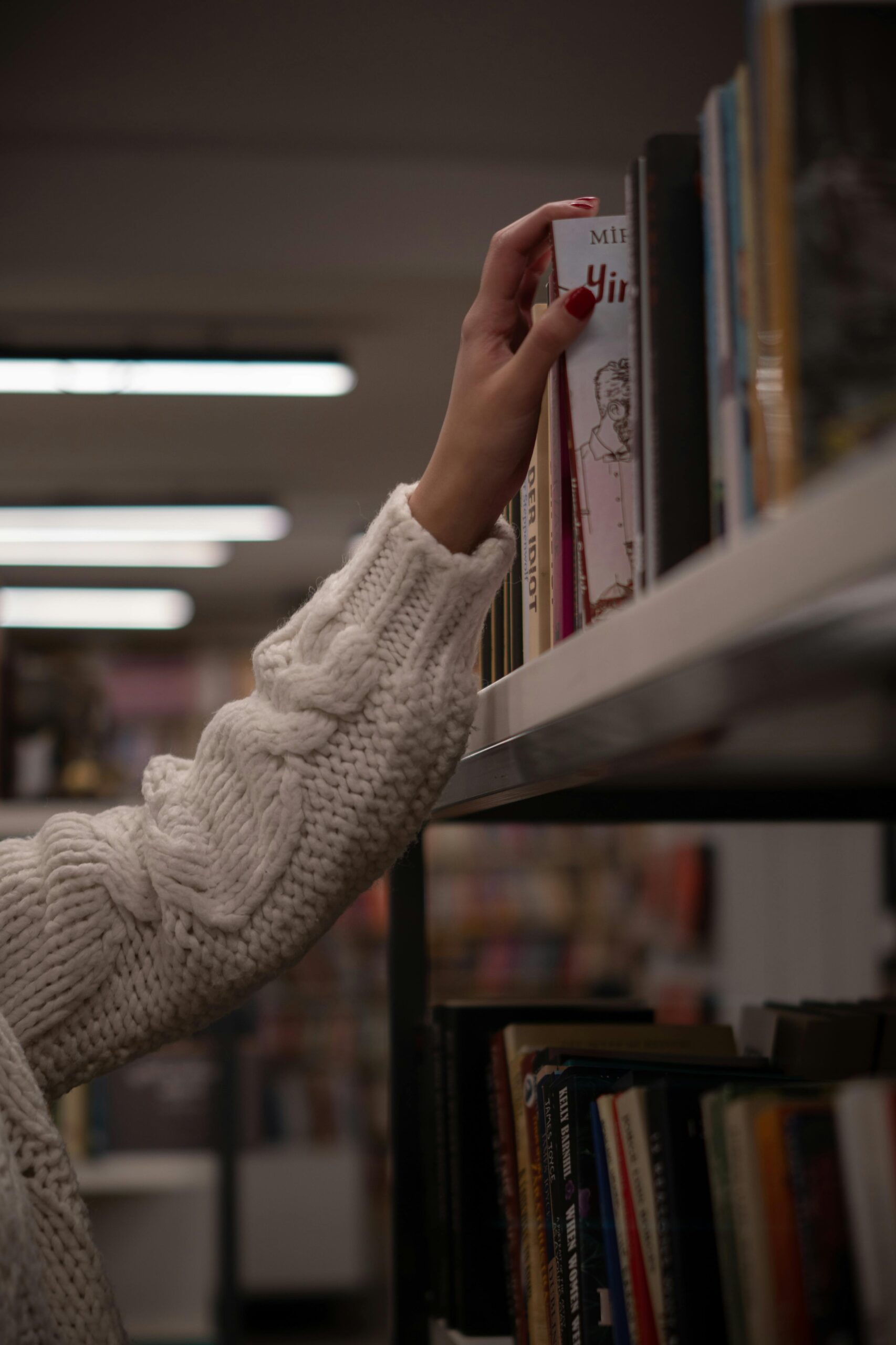 A beautiful girl selecting a book in the library